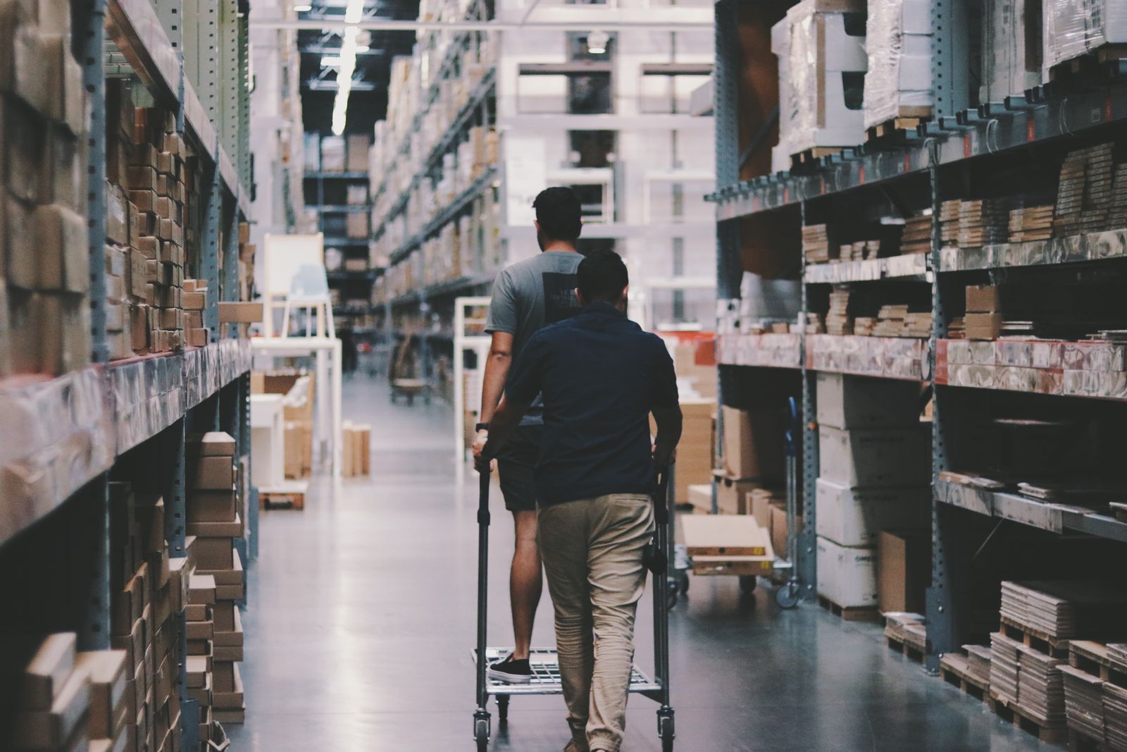 Two people moving a trolley through a warehouse